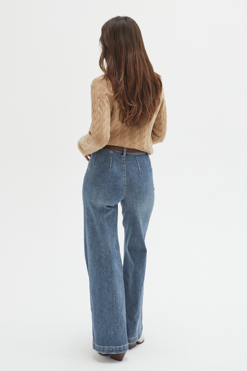 Back view of a model in medium blue high-rise wide-leg jeans, highlighting the tailored design and clean back pockets.