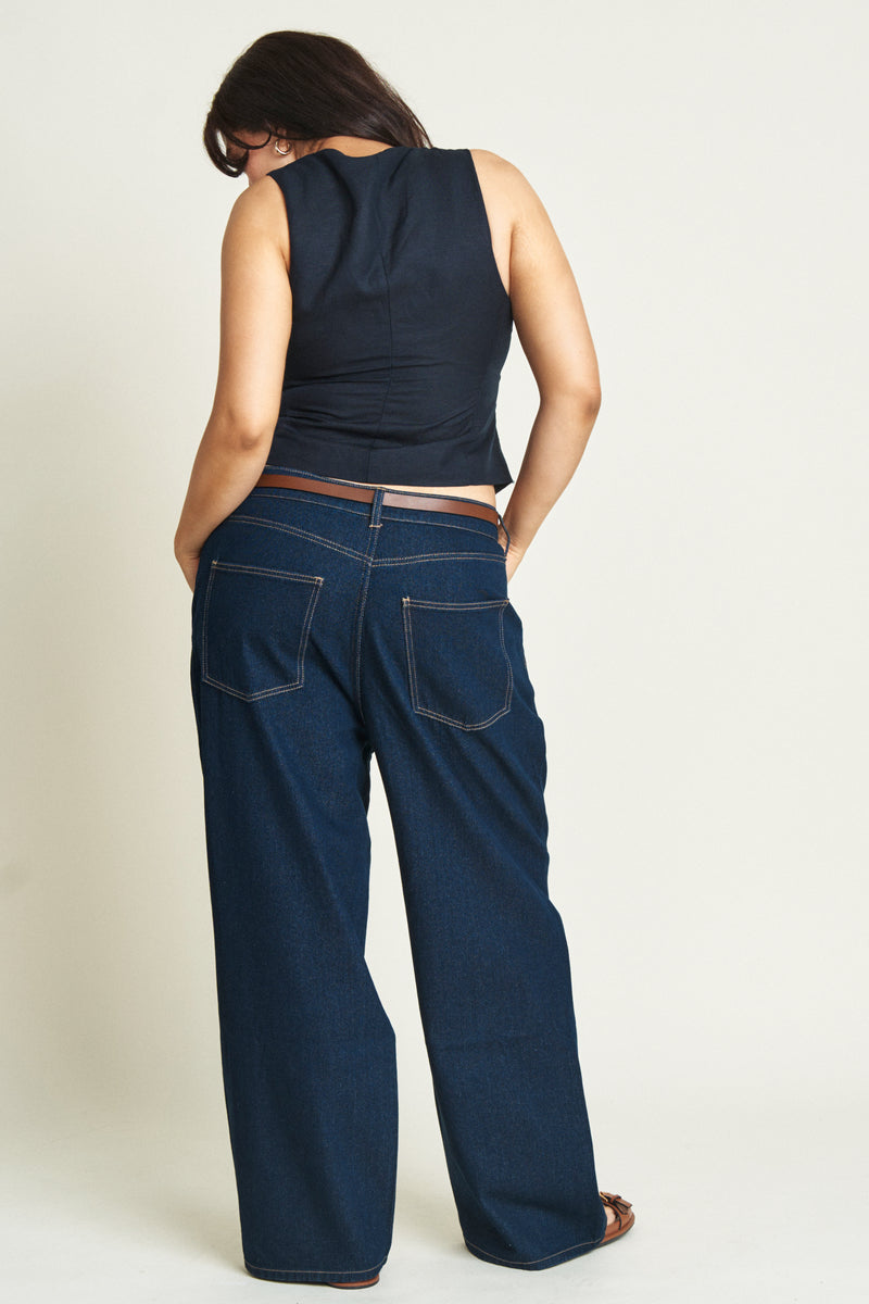 Back view of curvy model in low-rise, relaxed-fit baggy jeans, showcasing the deep blue wash and casual silhouette.
