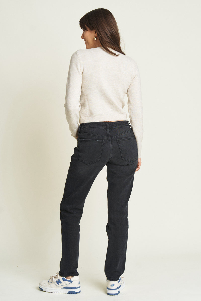 Back view of a model in black low-rise jeans, emphasizing the sleek design and tailored fit through the hips.
