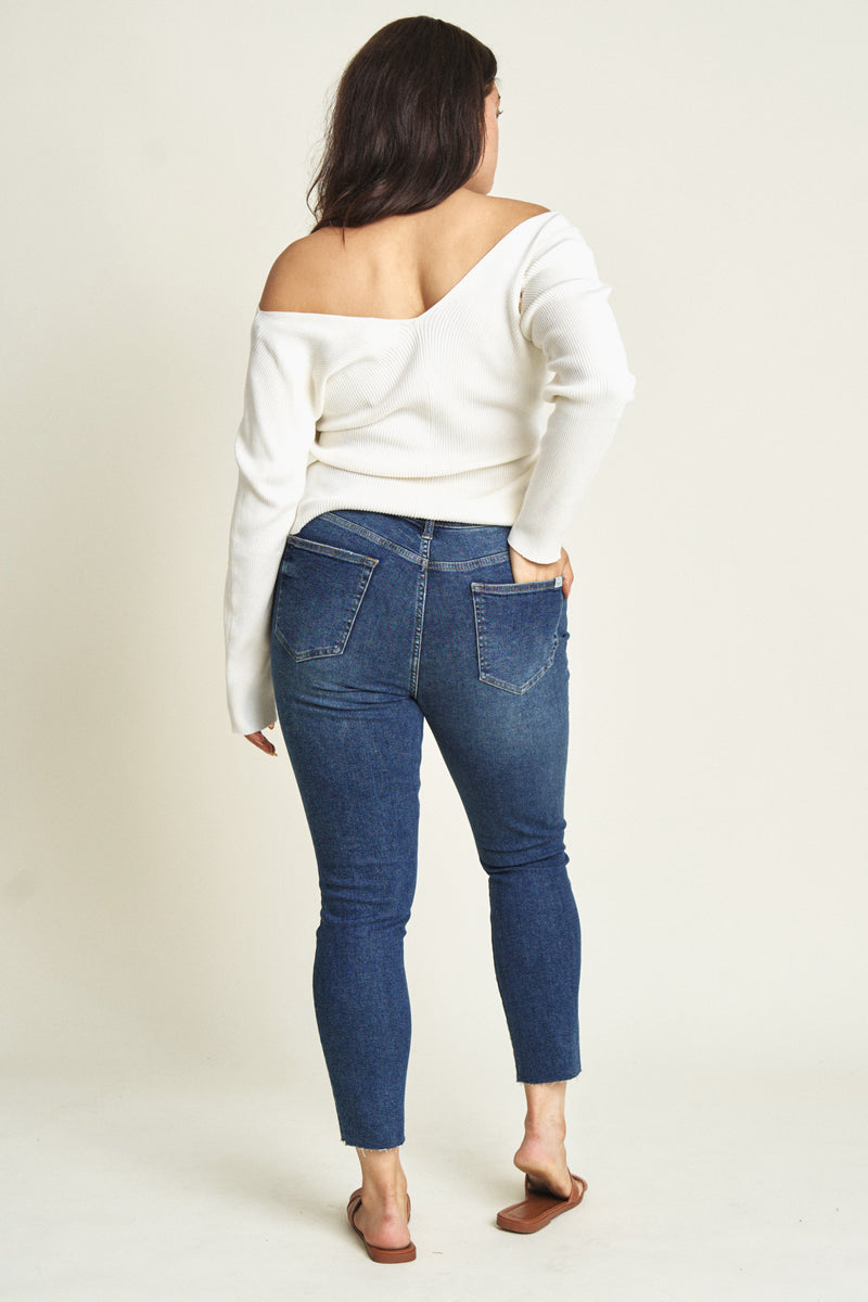 Back view of plus-size model in dark wash skinny jeans with a stretchy high rise fit.