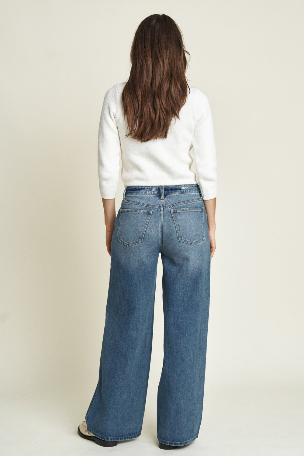 Back view of a model in mid-rise wide-leg jeans, emphasizing the clean back pockets and tailored seams.
