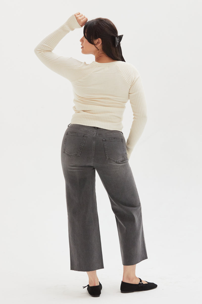  Back view of a model wearing gray wide-leg cropped jeans, highlighting the mid-rise waist and sustainable denim design.