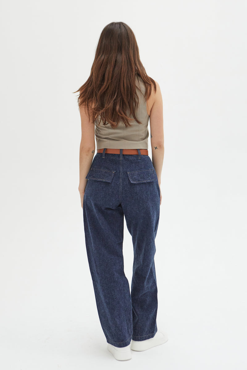 Back view of a model in dark indigo trouser jeans, highlighting the clean lines and tailored back pockets.
