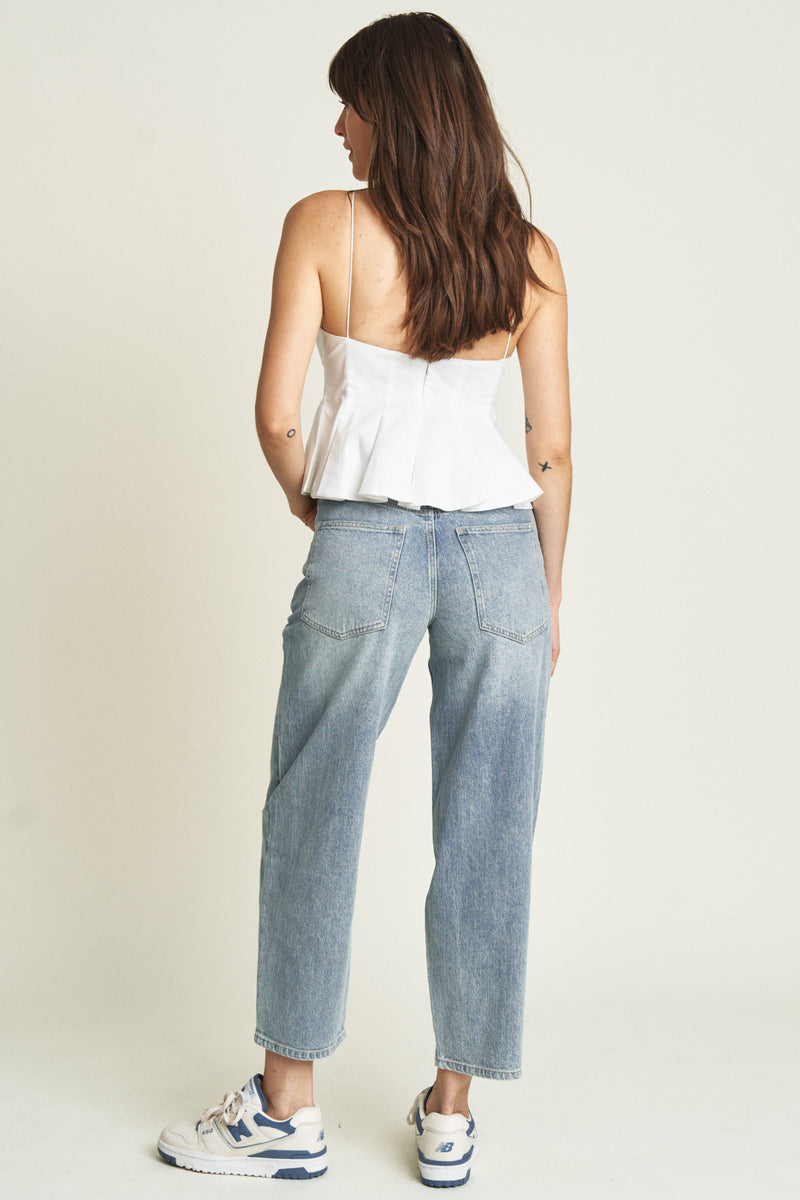 Back view of the model in light-washed barrel jeans, highlighting the high-rise design and relaxed silhouette.
