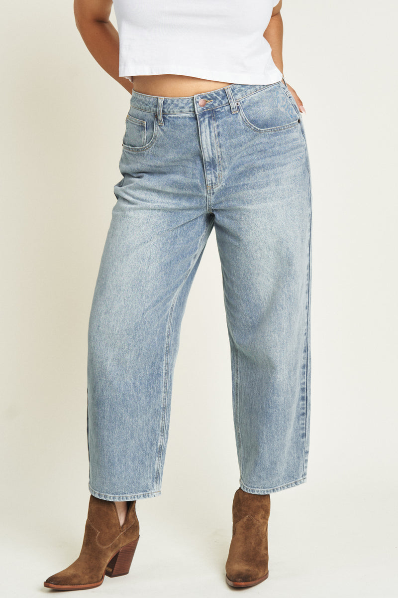 Close-up of light-washed barrel jeans, focusing on the waist and seam details, paired with ankle boots.