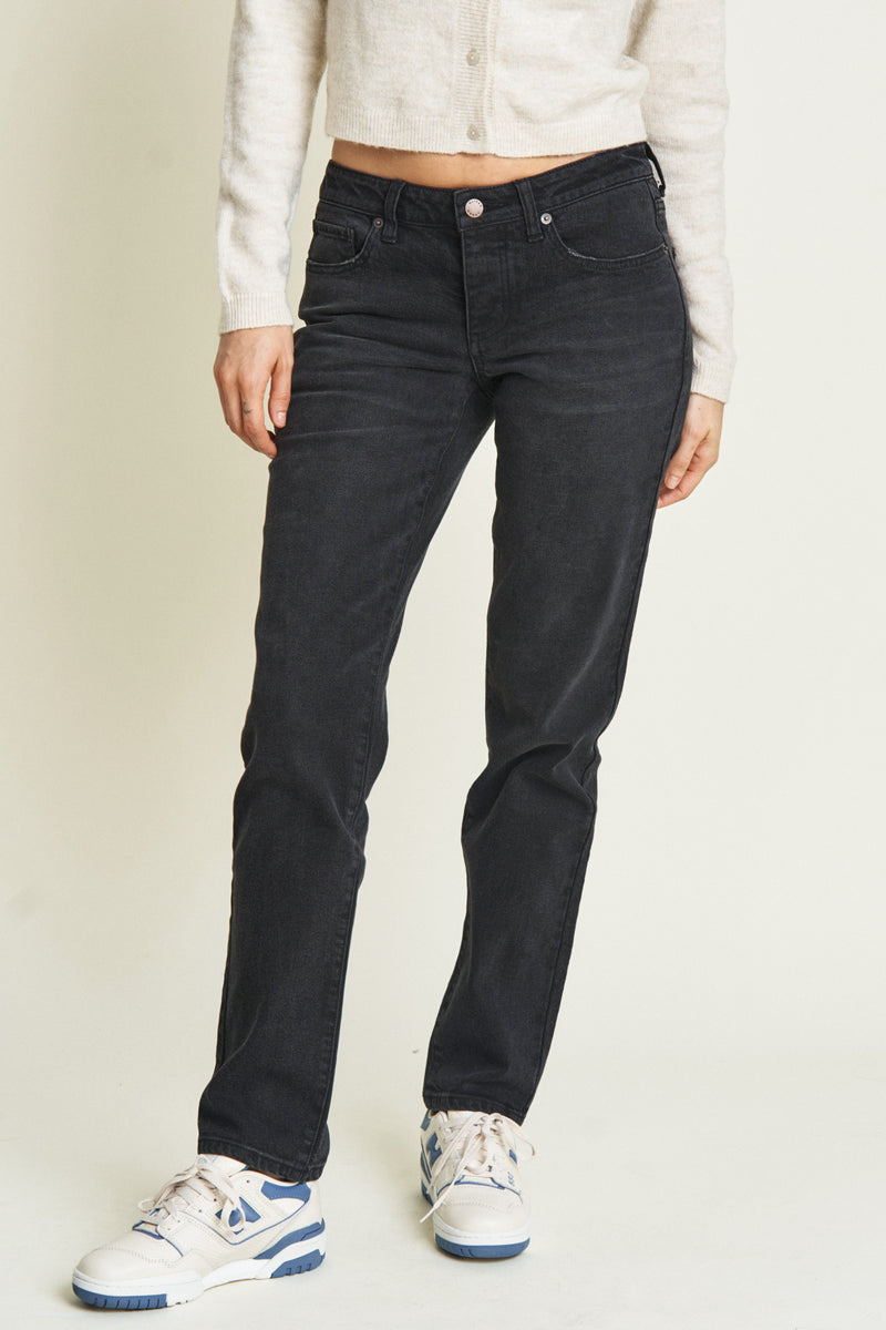 Close-up of black low-rise jeans, highlighting the durable denim material and subtle whiskering details.