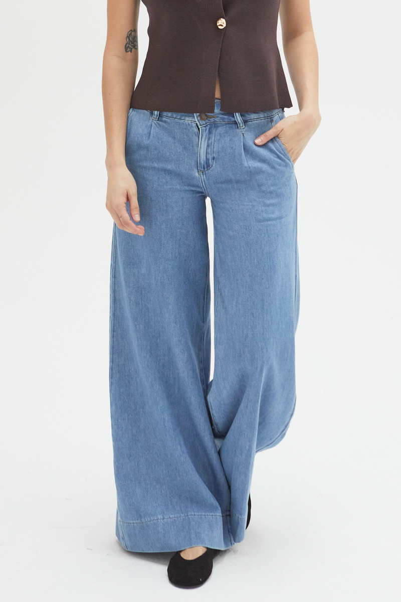 Close-up of lighter blue wide-leg pants, emphasizing the lightweight fabric, tailored pleats, and comfortable low-rise design.
