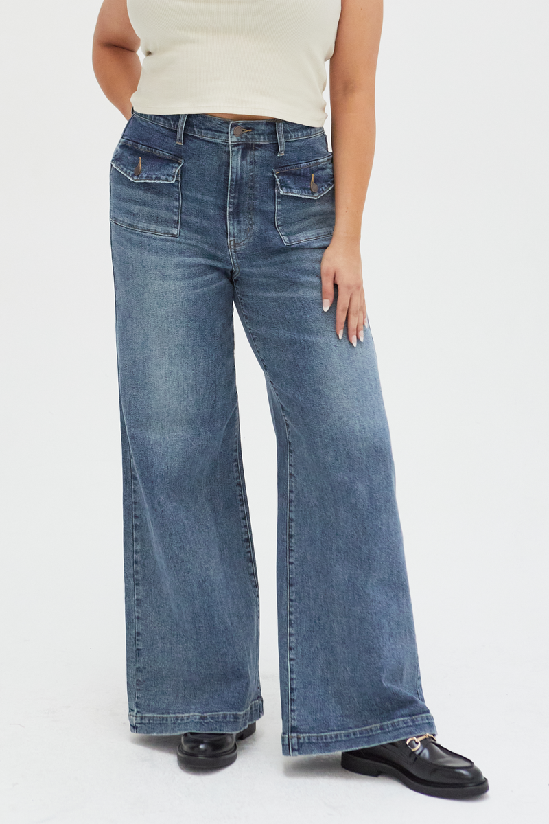 Close-up of medium blue high-rise wide-leg jeans, highlighting the durable denim fabric, structured seams, and high-rise waistline.