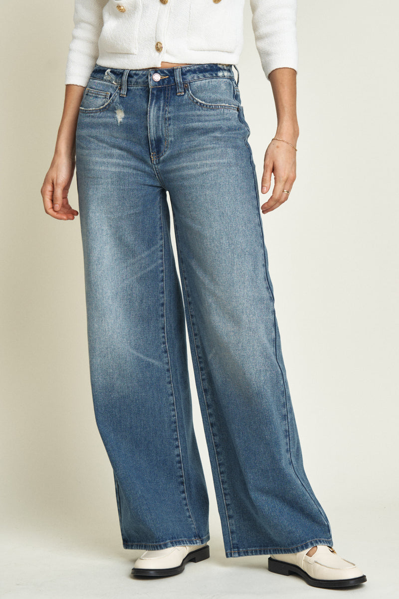 Close-up of medium blue wide-leg jeans, highlighting the soft denim fabric, mid-rise waistband, and subtle fading.