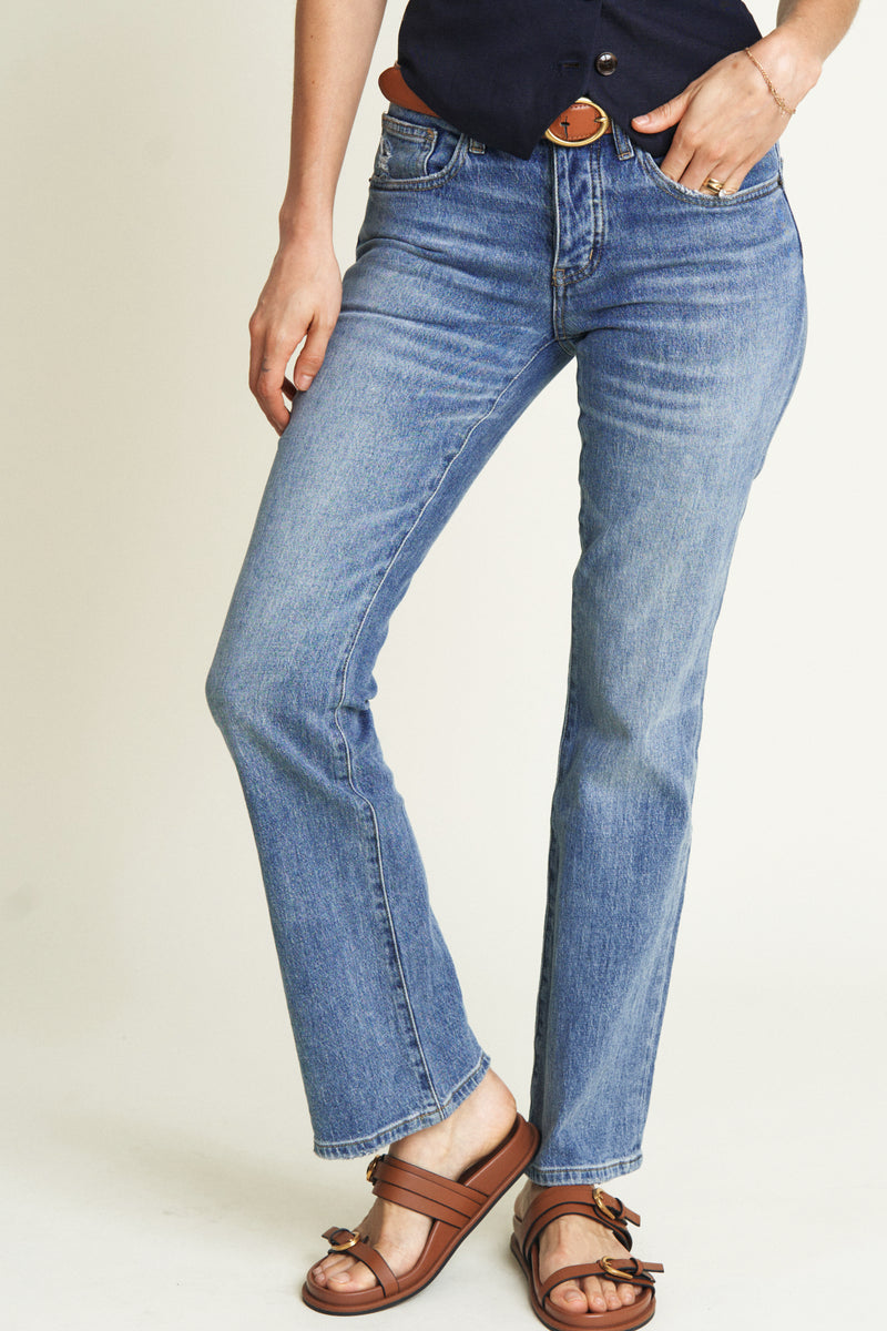 Close-up of light wash bootcut jeans, highlighting the button closure and relaxed mid-rise waist in vintage-style women&