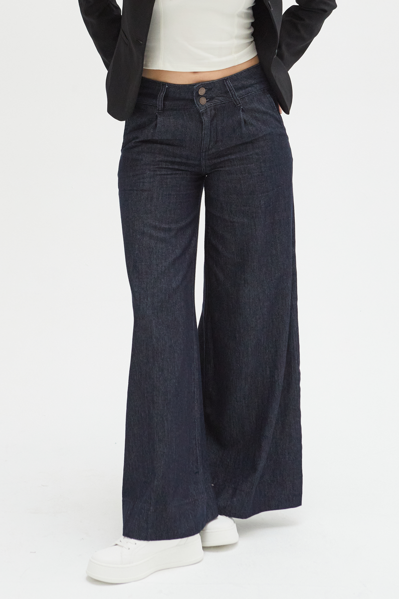 Close-up of dark wash wide-leg pants, highlighting the pleated front design, durable fabric, and comfortable low-rise waistband.
