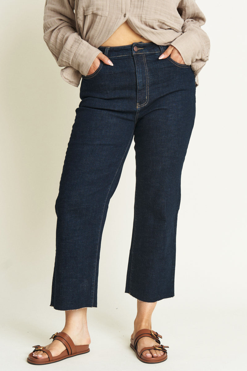 Close-up of women from the hip down wearing cropped dark denim jeans.