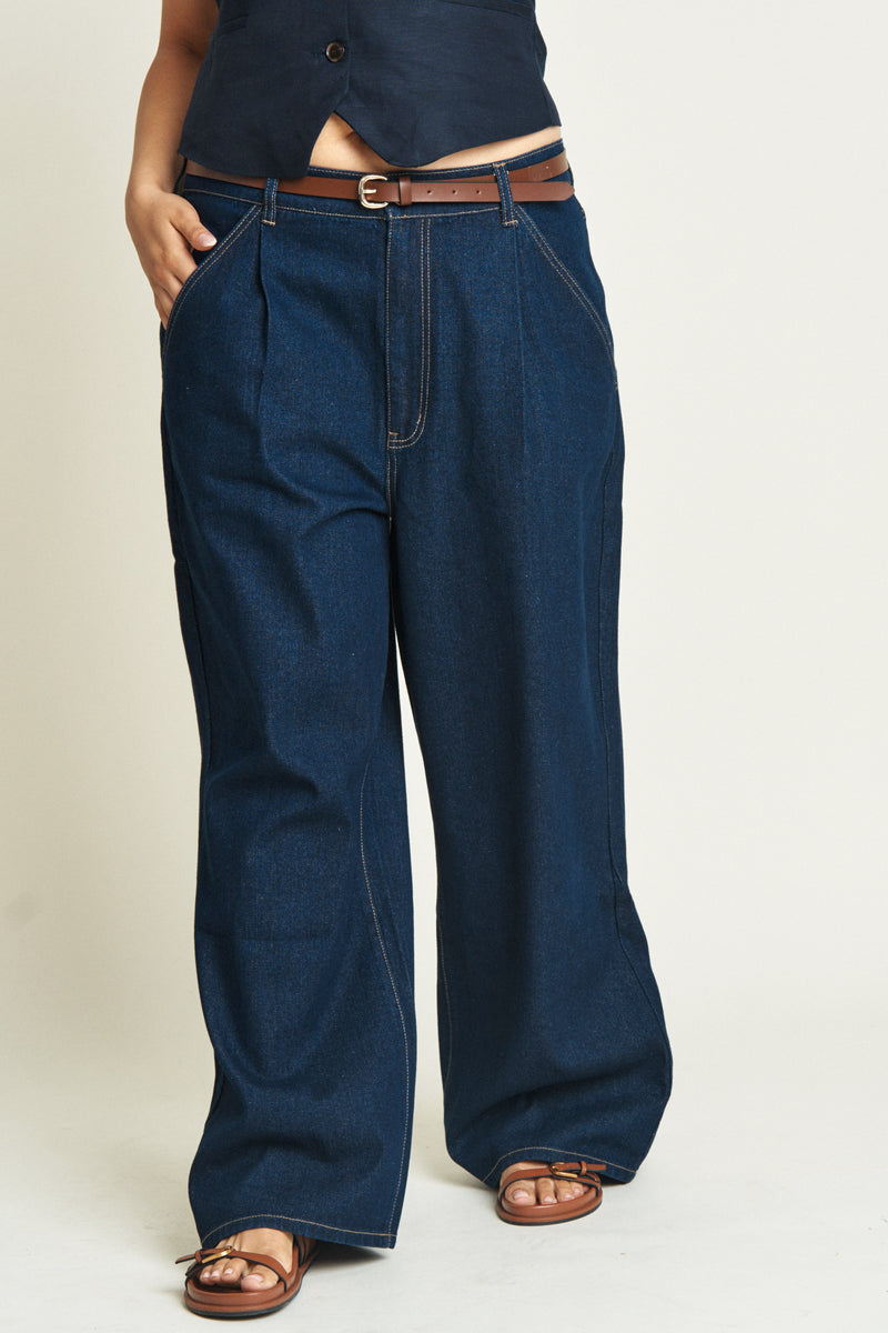 Close-up of dark blue low-rise baggy jeans on a curvy model, emphasizing the super relaxed fit and durable denim material.