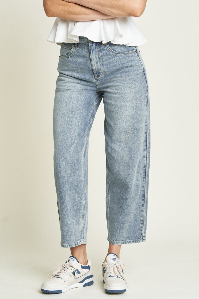 Close-up view of light-washed barrel jeans, focusing on the high-rise waist and light wash details.