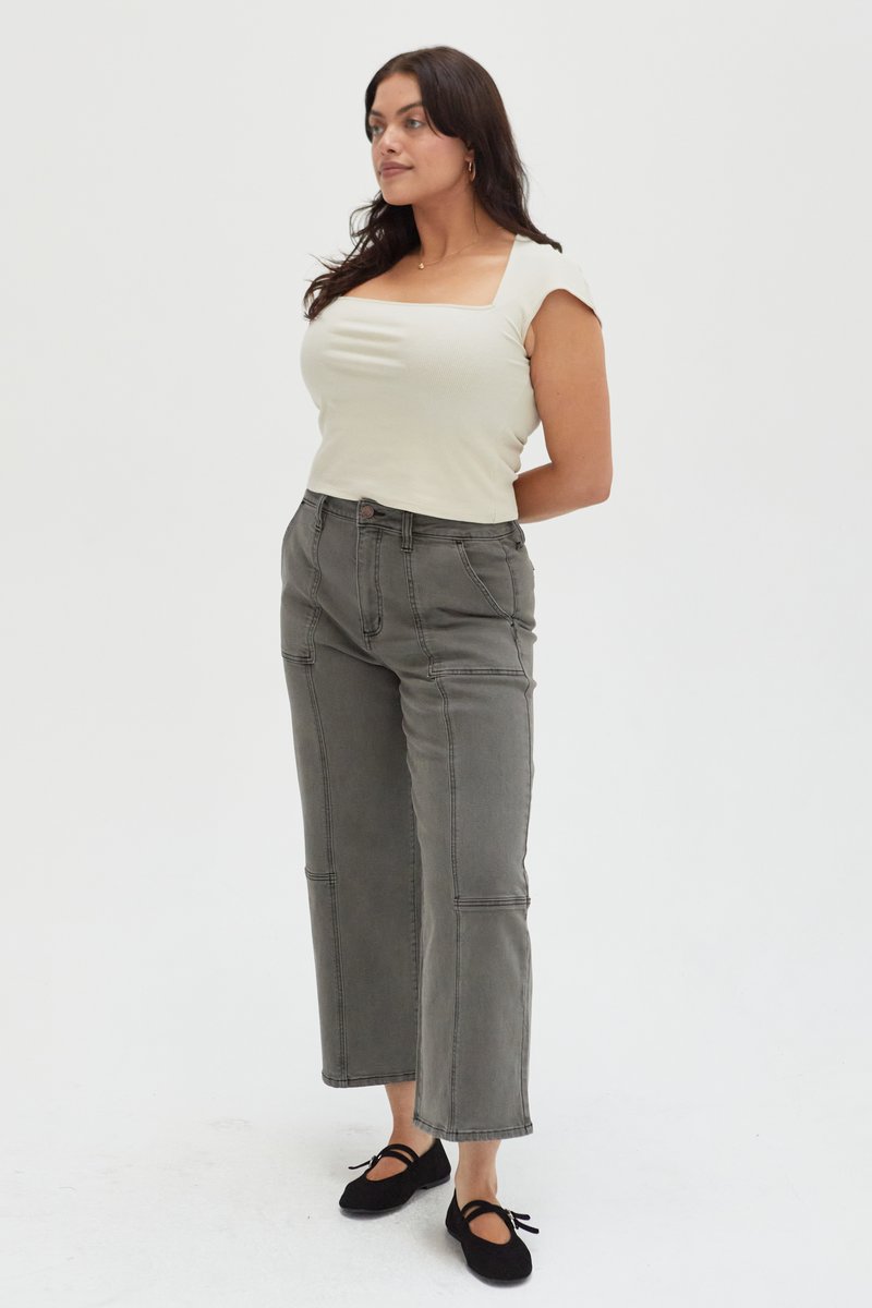 Side view of a plus-size model in olive wide-leg ankle crop jeans, styled casually with a neutral top, showcasing their modern and versatile design.