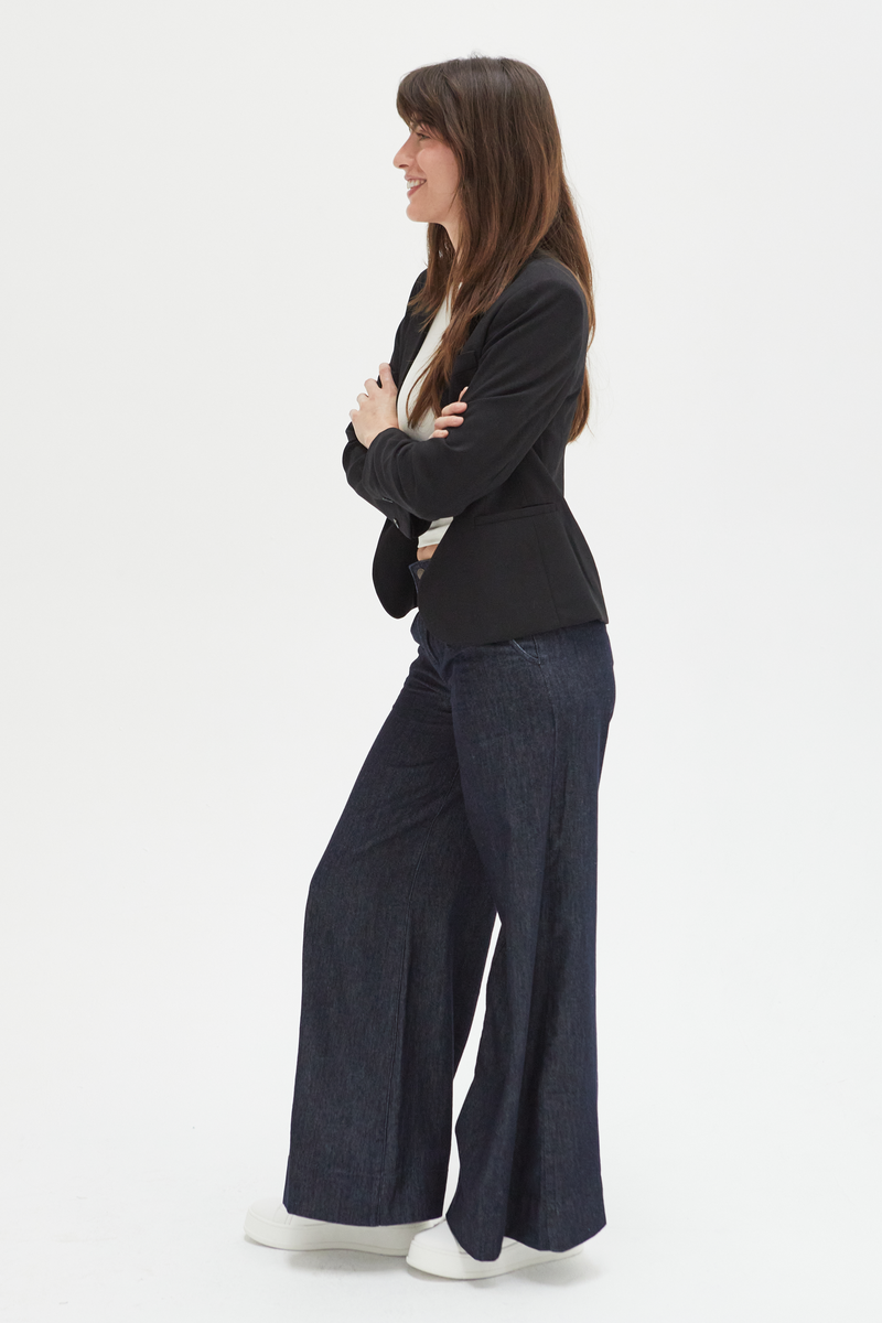 Side view of a model in dark wash wide-leg trousers, paired with a sleek blazer, showcasing their modern and versatile style.
