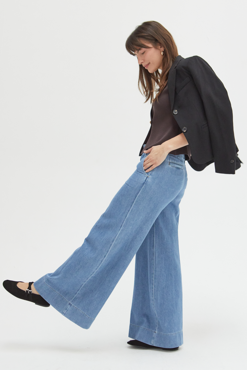 Side view of a model in lighter blue wide-leg trousers, paired with a casual top, showcasing their breezy and stylish appeal.
