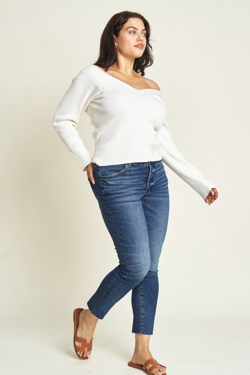 Side view of plus-size model in stretchy dark wash skinny jeans, paired with brown sandals.