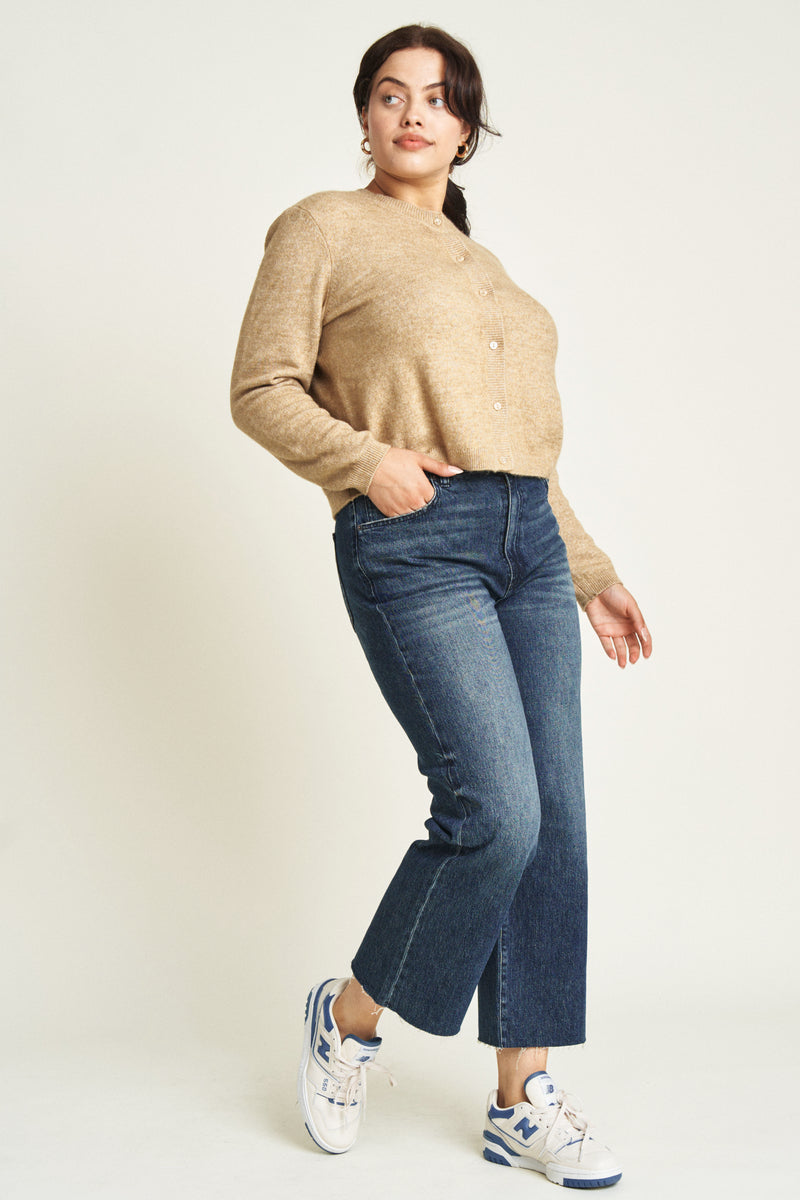 Side view of a curvy model in dark blue ankle crop jeans, paired with a casual jacket, showcasing their chic and versatile appeal.
