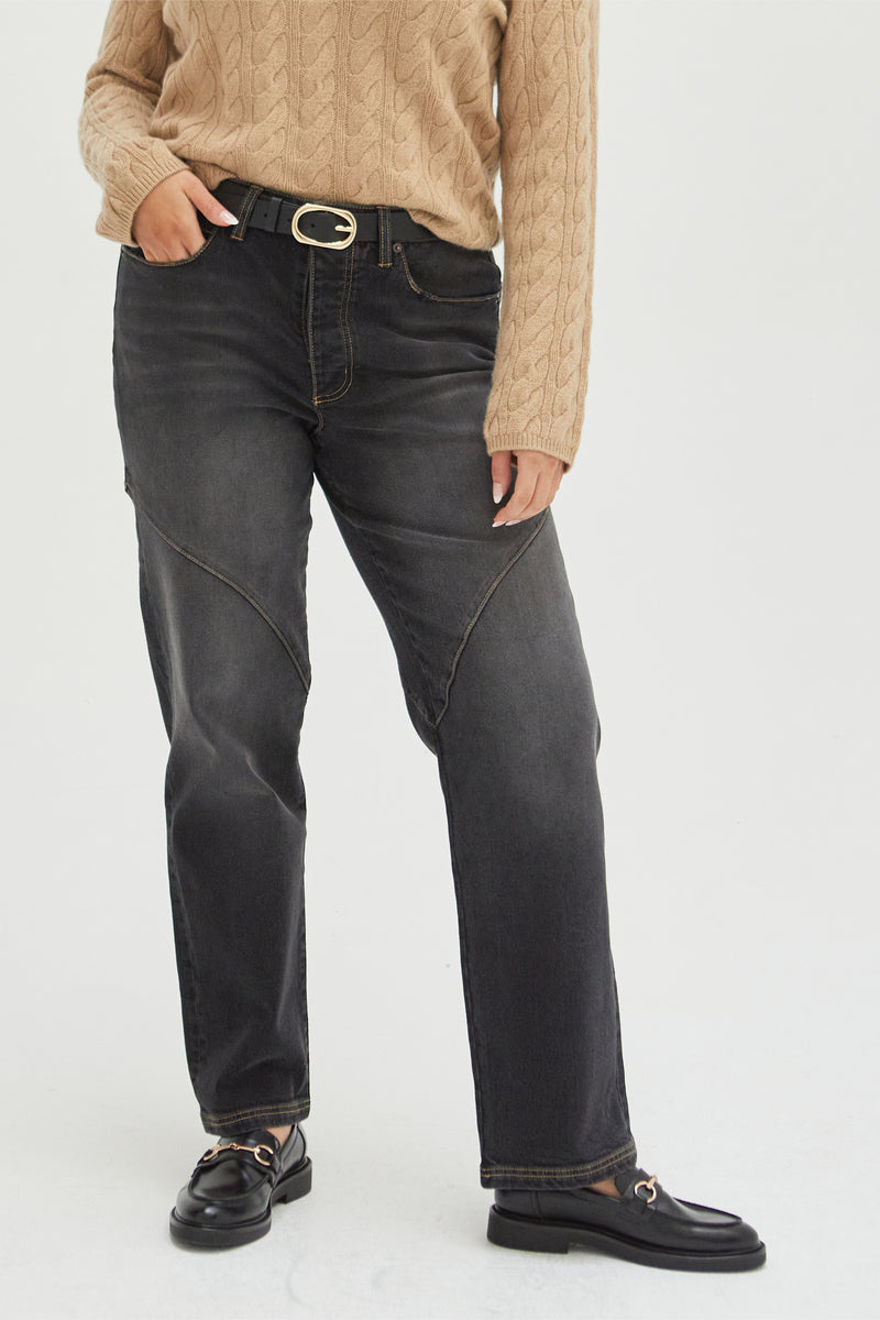  Close-up of high-rise straight leg jeans with seam detailing, paired with a black belt, emphasizing the flattering fit and durable material.
