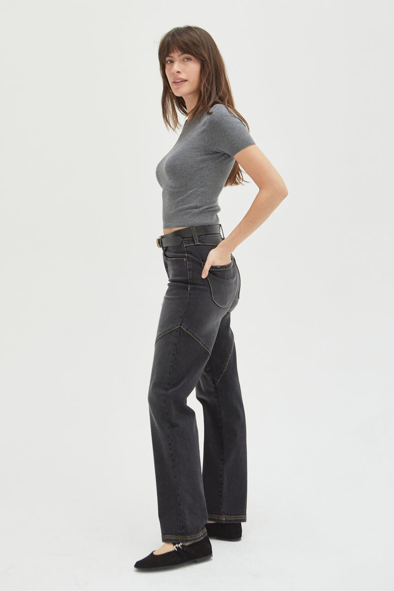 Side view of a model wearing high-rise straight fit jeans, paired with a black belt, showcasing timeless style and comfort.
