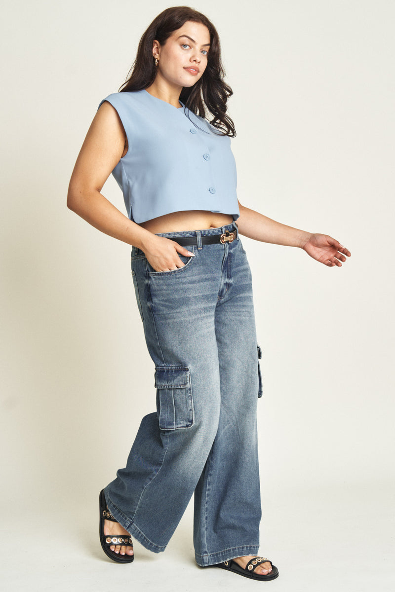 Side view of plus-size model in darker blue sustainable cargo jeans, highlighting wide-leg cut and practical pocket details.