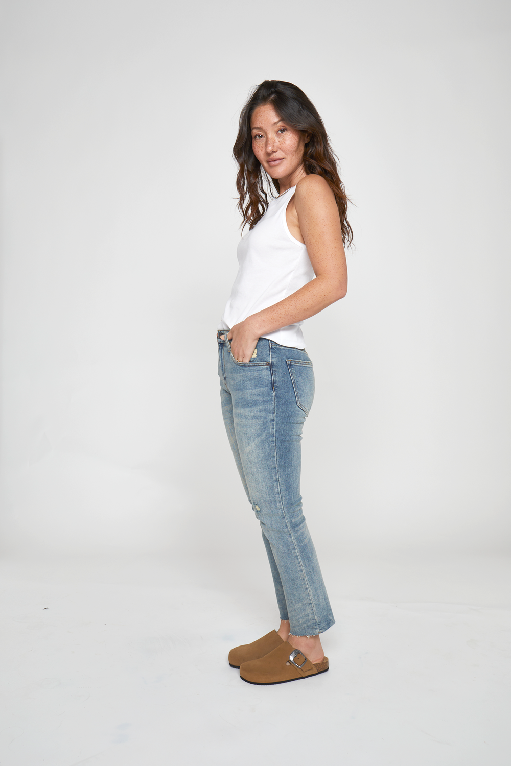 Side view of petite model in high rise vintage jeans, showing off the straight leg and relaxed fit paired with neutral flats.