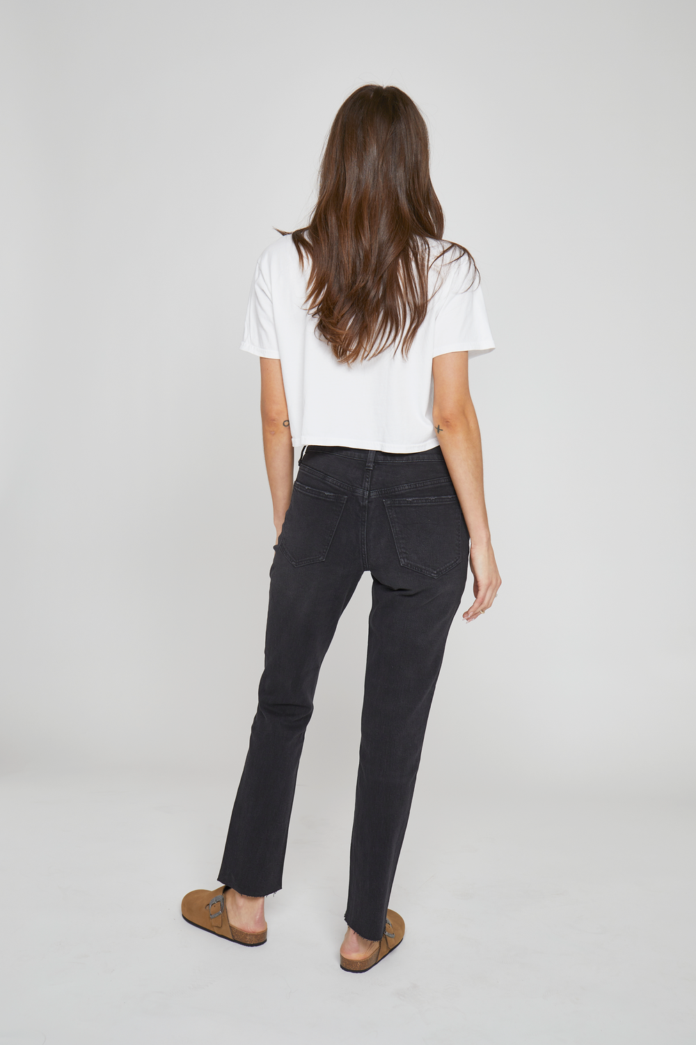 Back view of a model in black high-rise tapered-leg jeans, emphasizing the tailored fit and clean seam design.