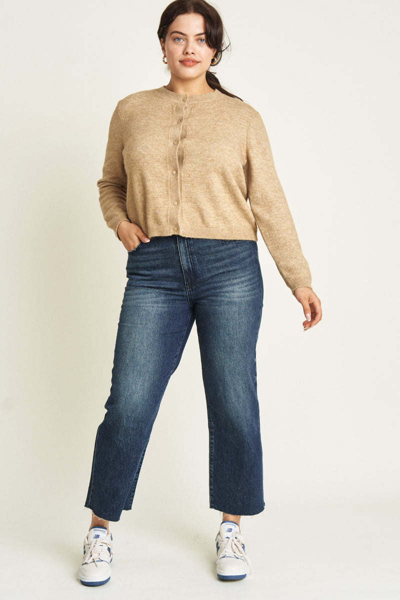 Curvy model moving in dark blue ankle crop jeans, demonstrating their flexible fit and everyday comfort.