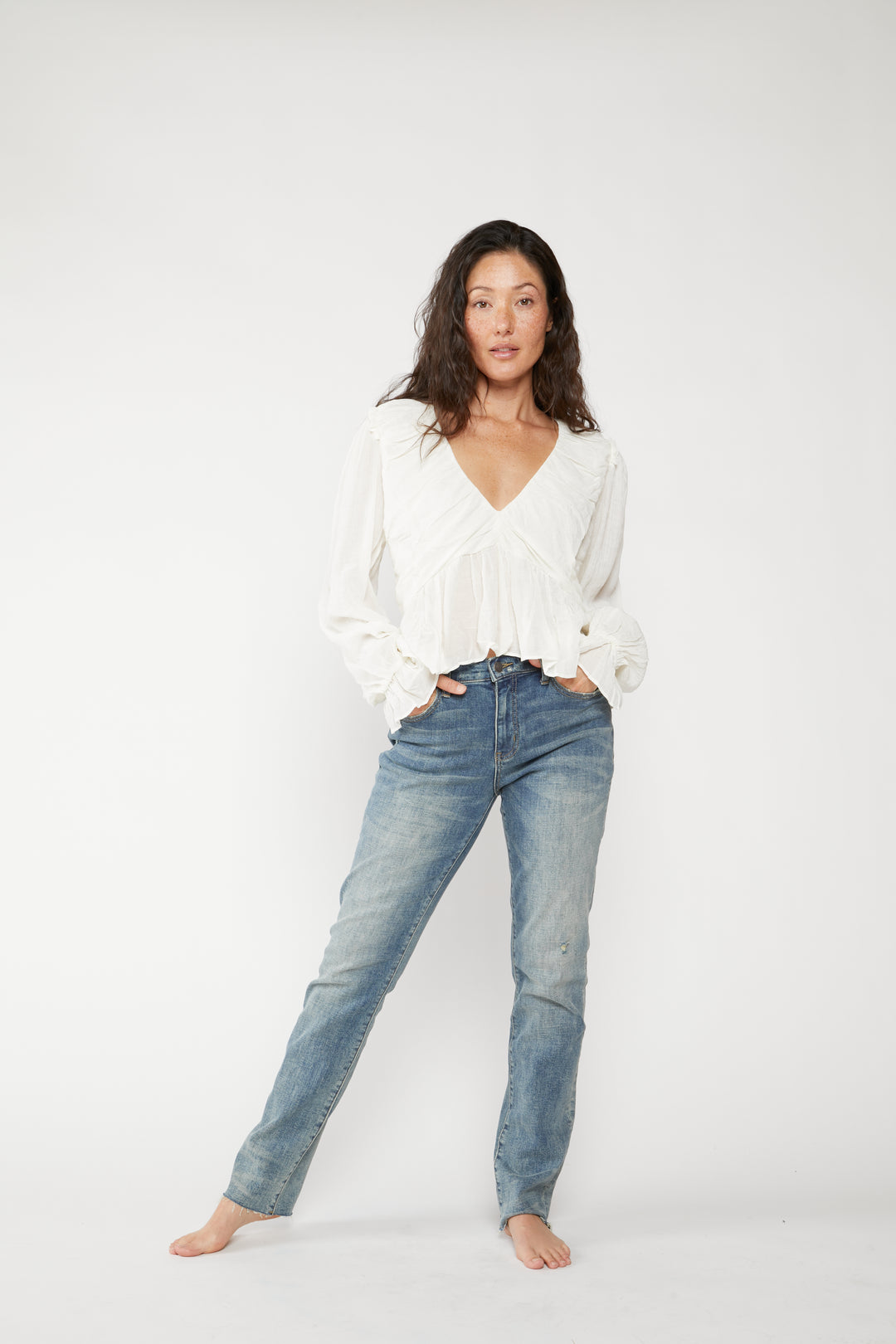 Petite model wearing high rise straight leg jeans in classic blue denim, paired with a white tank top, front view highlighting the slim fit.